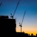 Silhouette of construction cranes at sunset.