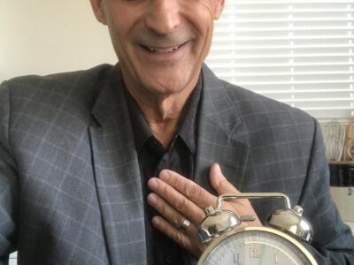 A man in a suit holding an alarm clock.