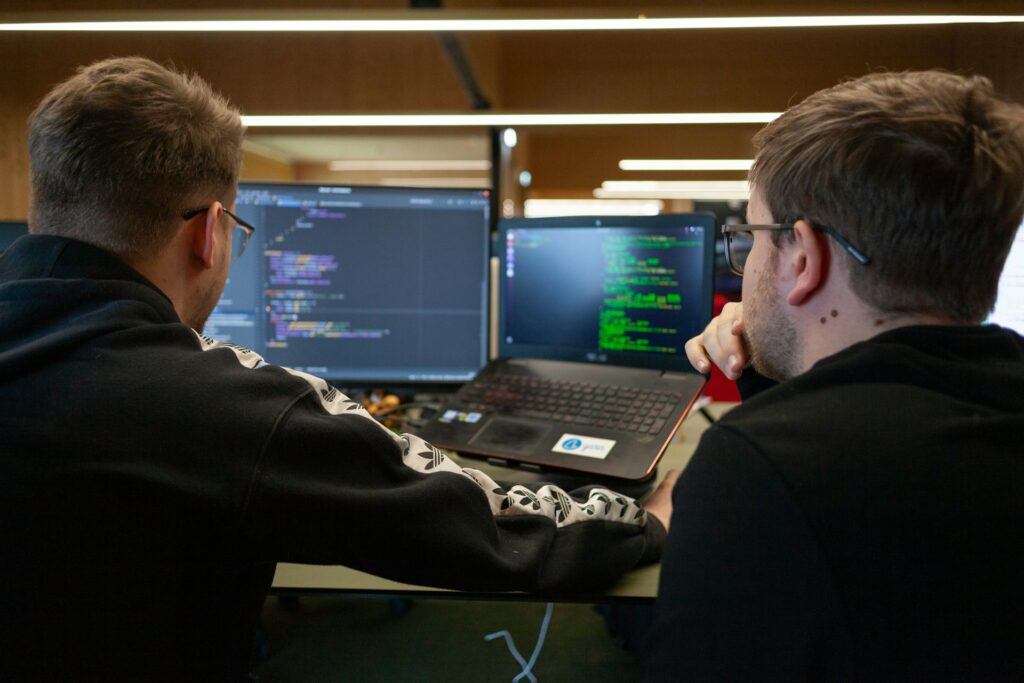 Two men looking at two computer screens, in an MSP office acting as an outsourced IT department