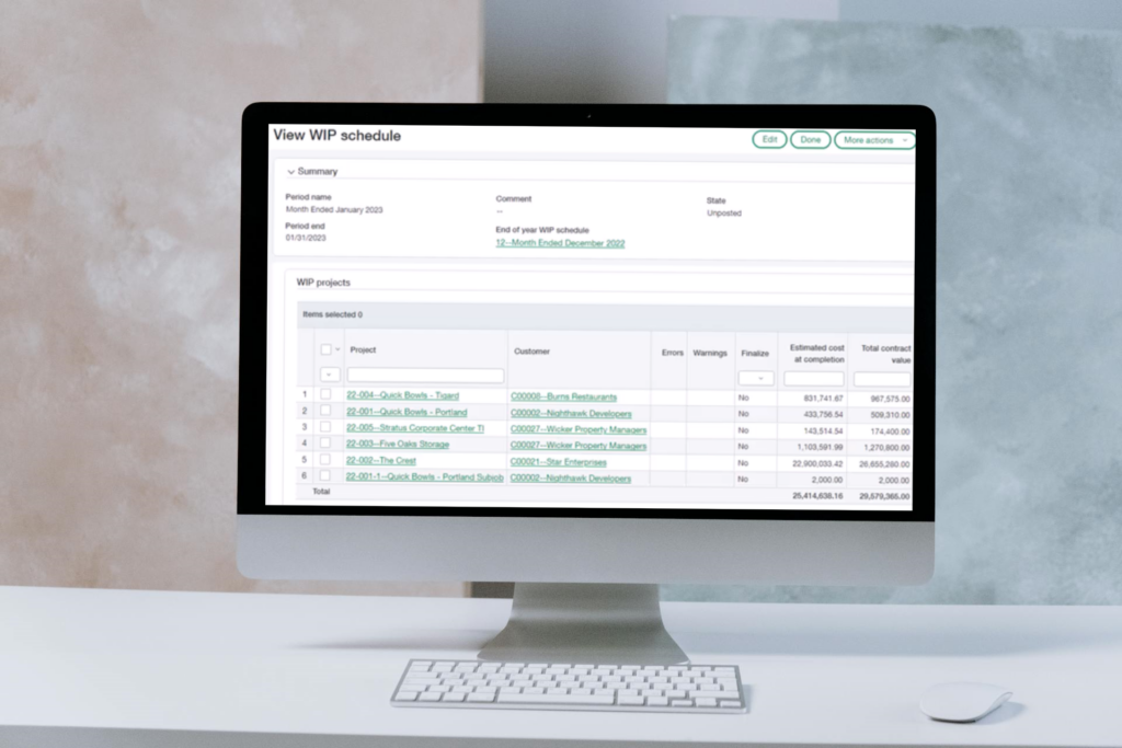 A Sage Intacct 2024 R4 Construction WIP schedule screen showing project details including customer names, estimated costs, and total contract values displayed on an iMac monitor against a light background.