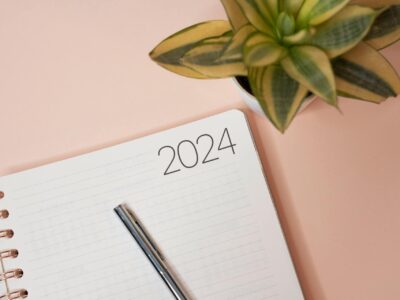 A notebook opened to a blank page marked "2024" with a pen placed across it, representing preparation for Sage 100 year-end closing procedures and tax reporting for the upcoming fiscal year.