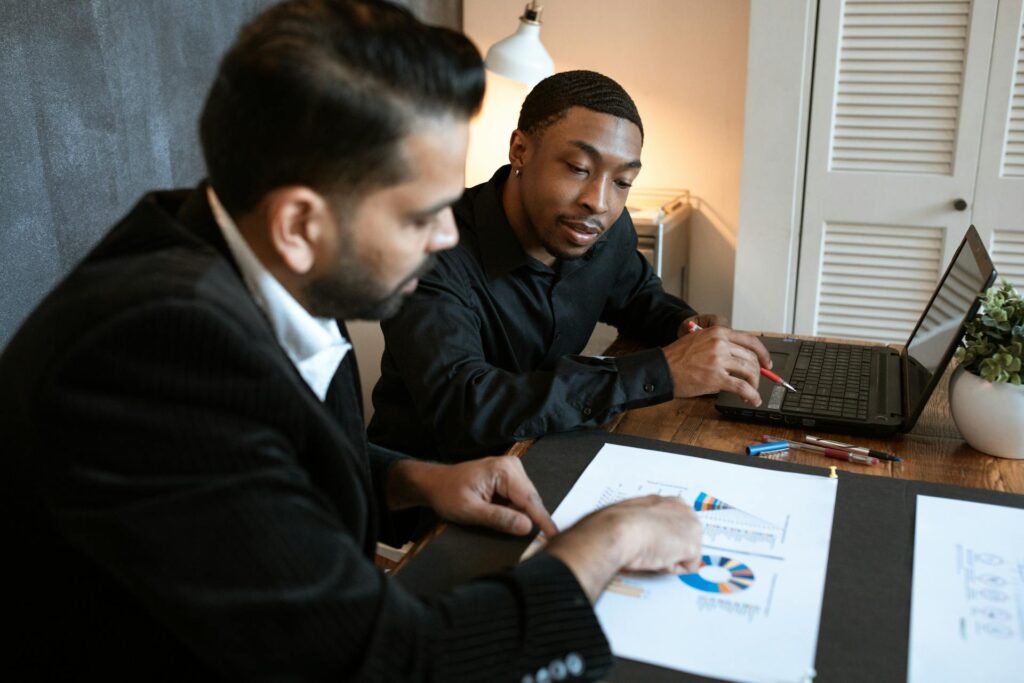 Two professionals in business attire closely examining documents and a laptop, demonstrating the hands-on support and guidance that SWK's expert consultants provide for Sage HRMS year-end processes.