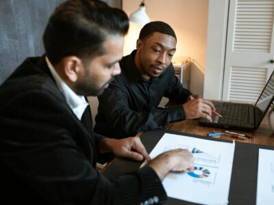 Two professionals in business attire closely examining documents and a laptop, demonstrating the hands-on support and guidance that SWK's expert consultants provide for Sage HRMS year-end processes.