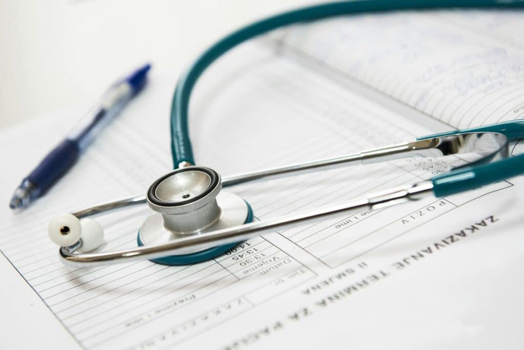 A medical stethoscope resting on patient health forms with a blue pen nearby, symbolizing healthcare documentation and professional IT services for medical facilities.