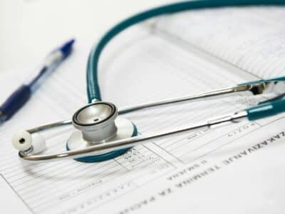 A medical stethoscope resting on patient health forms with a blue pen nearby, symbolizing healthcare documentation and professional IT services for medical facilities.