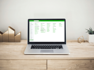 A MacBook laptop displaying the Acumatica ERP System Management interface on a wooden desk.