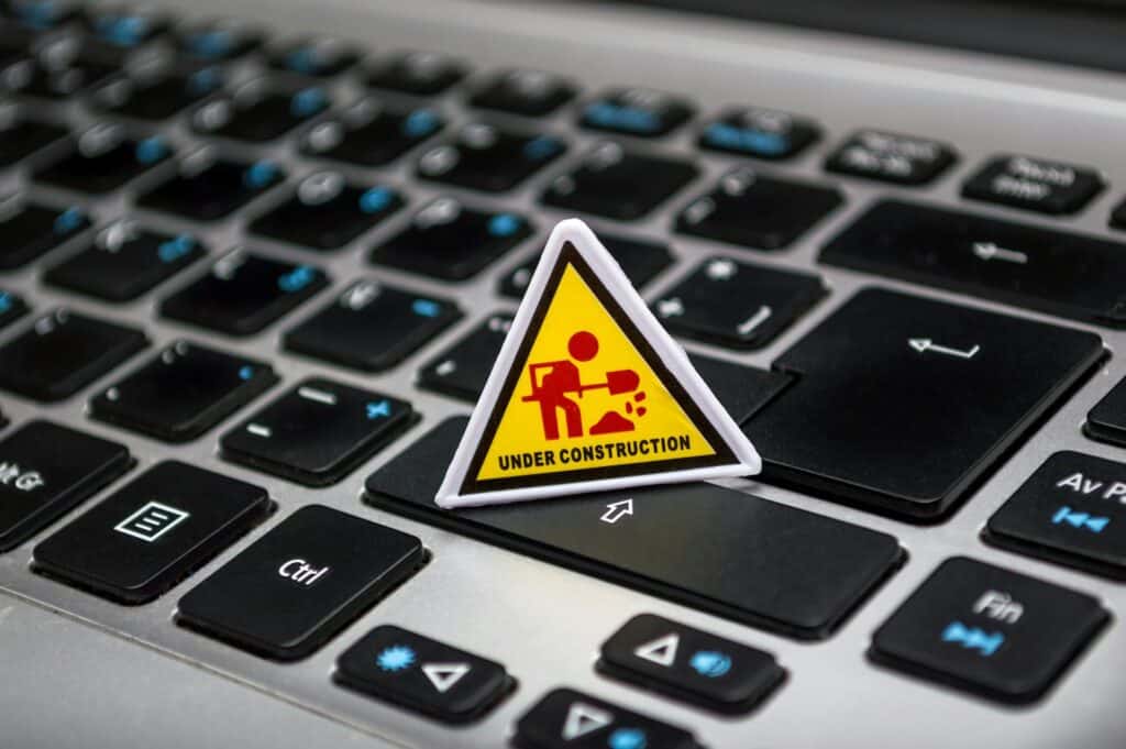 A small yellow triangular "Under Construction" sign placed on a laptop keyboard, symbolizing system upgrades and maintenance—relevant for planning Acumatica ERP upgrades where temporary system work leads to improved functionality.