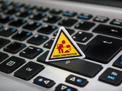 A small yellow triangular "Under Construction" sign placed on a laptop keyboard, symbolizing system upgrades and maintenance—relevant for planning Acumatica ERP upgrades where temporary system work leads to improved functionality.