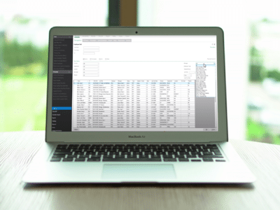 MacBook Air laptop displaying the Sage HRMS Employee Find interface with the More Options filtering panel expanded. The screen shows an employee list with detailed information including names, job titles, departments, and employment status for HR reporting purposes.